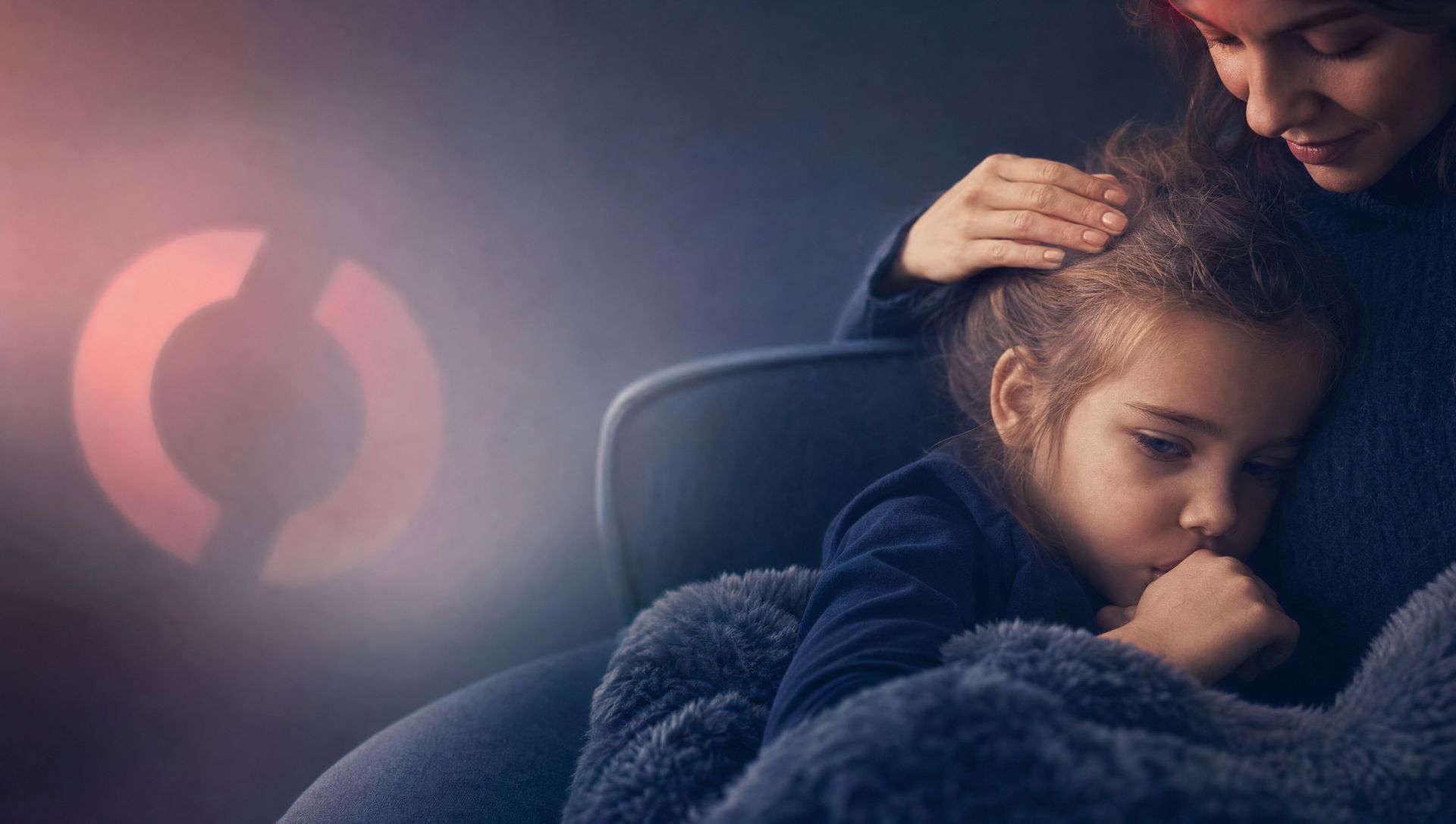 Müdes Kind kuschelt sich mit der Mutter auf das Sofa