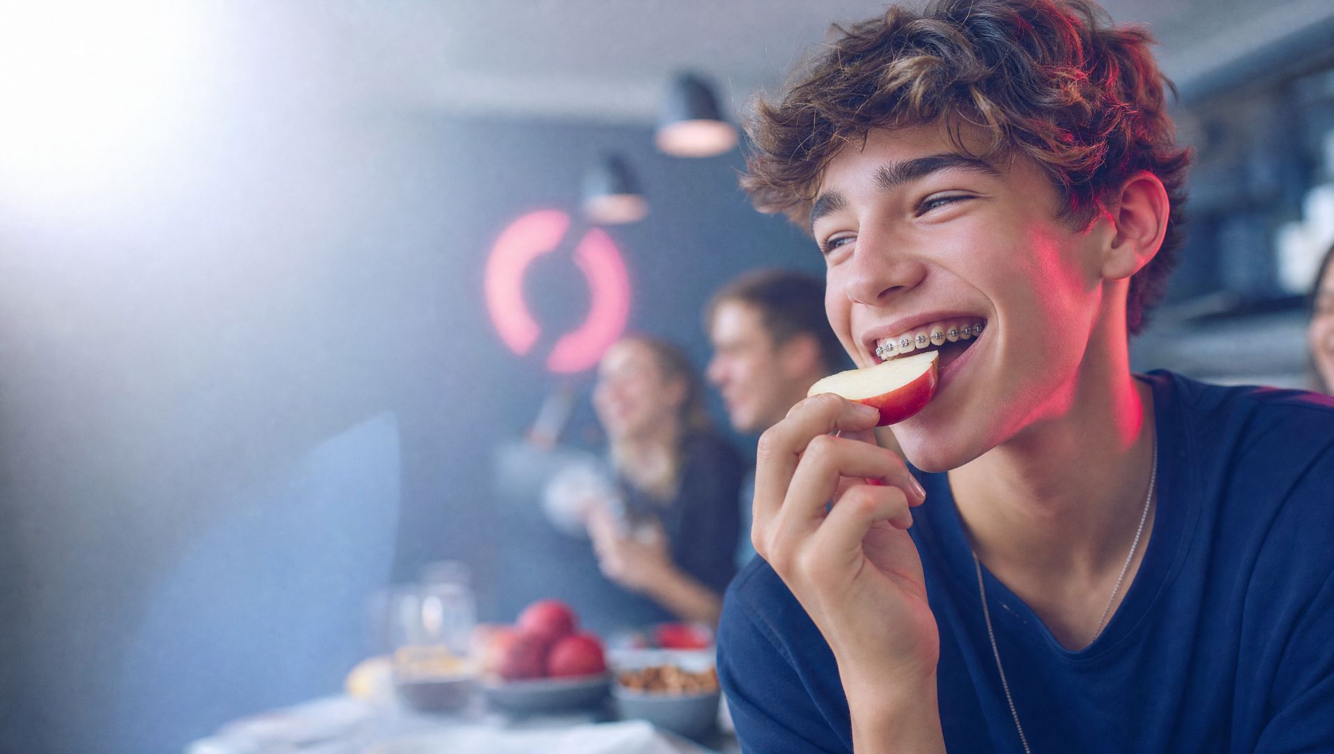 Jugendlicher mit Zahnspange beißt in einen Apfel