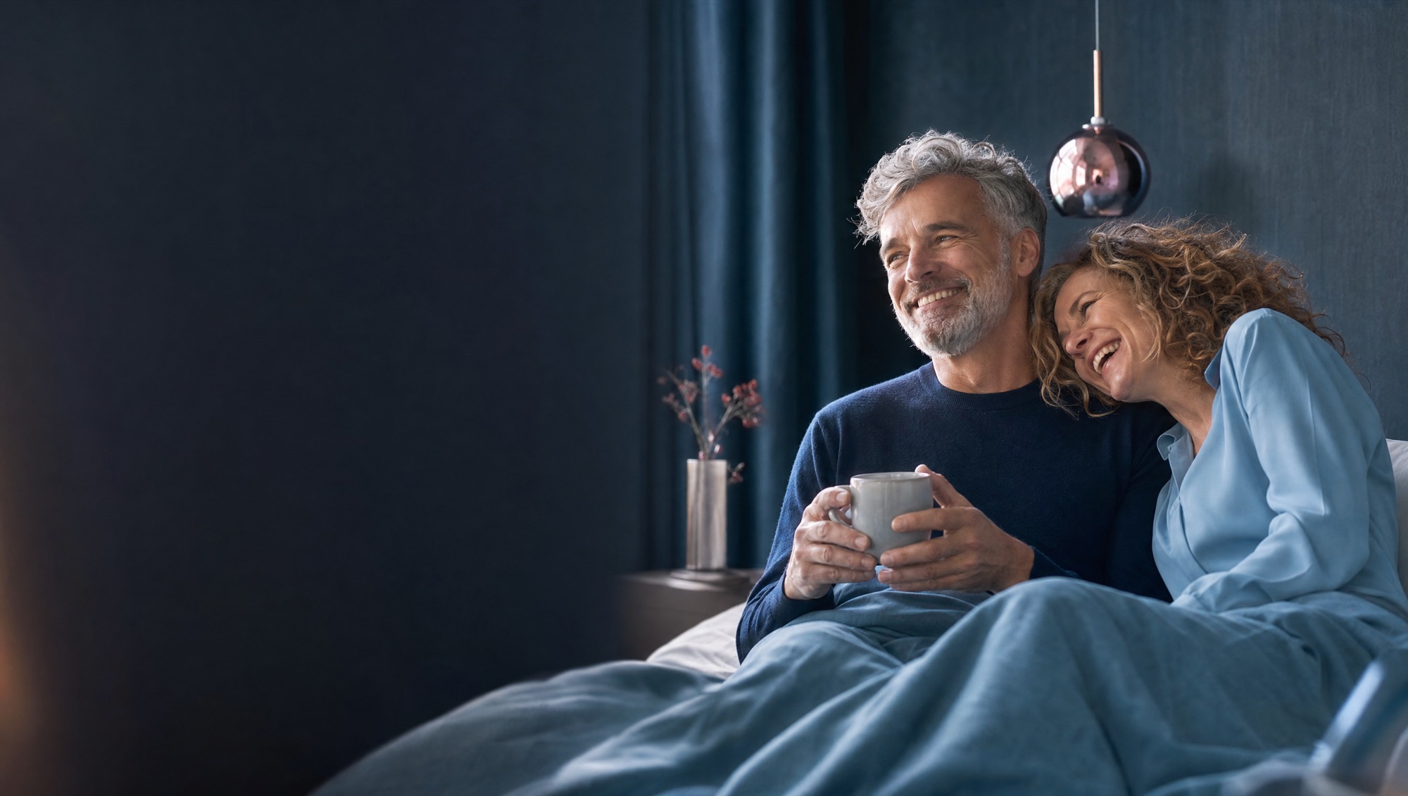 Erholtes Paar am Morgen im Bett mit Kaffee